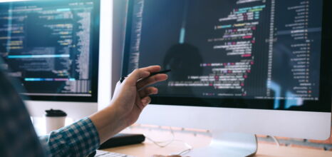 Mann deutet mit Stift auf einen Computer