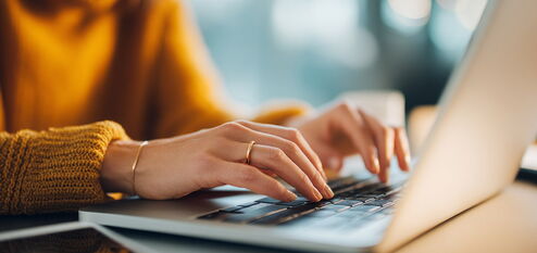 Jemand arbeitet konzentriert am Laptop in gemütlicher Atmosphäre