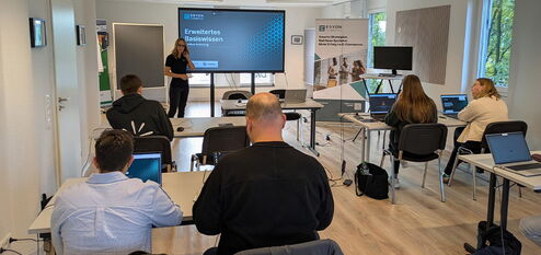 ESYON Schulung mit Vortragender vor Bildschirm und Teilnehmenden mit Laptops
