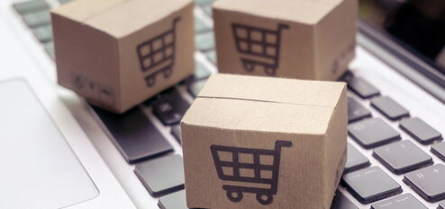 Pakete mit Einkaufswagen bedruckt liegen auf einer Tastatur