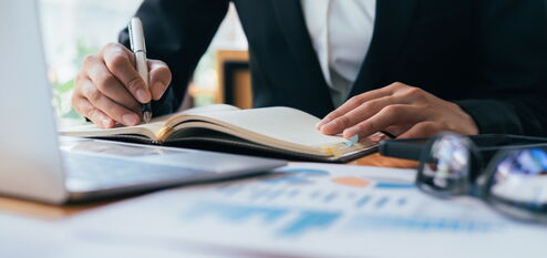 Mensch schreibt in ein Notizbuch