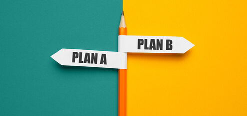 Bleistift mit Schildern Plan A und Plan B vor geteiltem Hintergrund in Türkis und Gelb