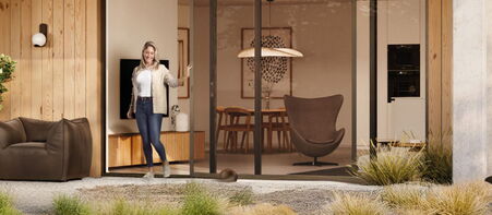 Frau öffnet moderne Glasschiebetür in einem stilvollen Wohnzimmer