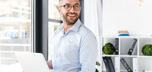Mann im Büro mit Laptop in der Hand
